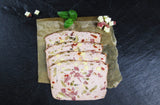 Vier scheiben Pizzafleischkäse gebacken vom EIFEL Schwein angerichtet mit Salamiwürfeln Käsewürfeln und Basilikum auf Backpapier mit Schieferhintergrund