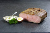 Roastbeefbraten am Stück und in Scheiben geschnitten mit gekochten Ei und Remouladensauce auf Schieferhintergrund