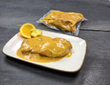 Hähnchenbrustfilets in Orangen Mango Sauce auf Teller und Kochbeutel auf Schieferhintergund