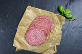 Land Cervelatwurst geschnitten mit Pfeffer und Basilikum auf Schieferhintergung