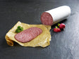 Haussalami angerichtet auf Backpapier mit Petersilie und Radieschen auf Schieferhintergrund