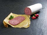 Haussalami angerichtet auf Backpapier mit Petersilie und Radieschen auf Schieferhintergrund