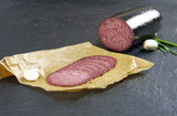 Rindersalami aufgeschnitten auf Backpapier auf Schieferhintergrund