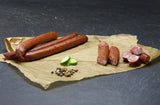 Pfeffer Schinkenmettwurst vom EIFEL Schwein mit Pfefferkörner und Gurke auf Schieferhintergrund