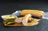 Fleischwürstchen vom EIFEL Schwein mit Gewürzgurken und einer Schüssel Senf auf Schieferhintergrund