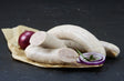 Bratwurst grob gebrüht mit Rosmarin und roten Zwiebeln auf Schieferhintergrund