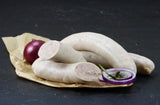 Bratwurst grob gebrüht mit Rosmarin und roten Zwiebeln auf Schieferhintergrund