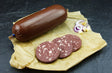 Hausmacher Blutwurst im Darm vom EIFEL Schwein mit roten Zwiebeln und Käsewürfeln auf Schieferhintergrund
