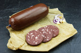 Hausmacher Blutwurst im Darm vom EIFEL Schwein mit roten Zwiebeln und Käsewürfeln auf Schieferhintergrund