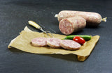 Hausmacher Schwartenmagen im Darm vom EIFEL Schwein mit Gurken und Cherry Tomaten auf Schieferhintergrund
