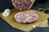 Schweinskopfsülze mit Gurken Riegel mit einer Zwiebel und einer Gewürzgurke auf Schieferhintergrund