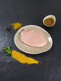 Schweinerückensteak Bombay auf Teller angerichtet mit einer Schale Bombay Marinade Gewürzen und Kräutern auf Schieferhintergrund