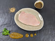 Schweinerückensteak Senfzauber auf Teller angerichtet mit einer Schale Senf Marinade Senfkörnern und Kräutern auf Schieferhintergrund