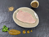 Schweinerückensteak Senfzauber auf Teller angerichtet mit einer Schale Senf Marinade Senfkörnern und Kräutern auf Schieferhintergrund