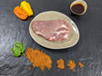 Schweinenackensteak Paprika auf Teller angerichtet mit einer Schale Marinade Paprikas Kräutern und Gewürzen auf Schieferhintergrund