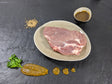 Schweinenackensteak Senfzauber auf Teller mit einer Schale Marinade Senfkörnern und Kräutern auf Schieferhintergrund