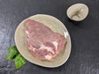 Schweinenackensteak natur auf Teller mit Kräutern auf Schieferhintergrund