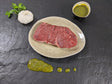 Rumpsteak Kräuter Knoblauch auf Teller angerichtet mit einer Schale Marinade Kräutern und Knoblauchknolle auf Schieferhintergrund
