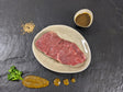Rumpsteak Senfzauber auf Teller angerichtet mit einer Schale Marinade Senfkörnern und Kräutern auf Schieferhintergrund