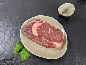 Entrecôte natur auf Teller mit Kräutern auf Schieferhintergrund