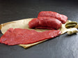 Rinder Rouladen aus der Oberschale auf Backpapier angerichtet mit Essiggurken und Silberzwiebeln auf Schieferhintergrund