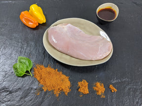 Putensteak Paprika auf Teller angerichtet mit einer Schale Marinade Paprikas Kräutern und Paprikapulver auf Schieferhintergrund