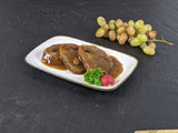 Sauerbraten Rheinischer Art auf Teller angerichtet mit Petersilie Radieschen und Trauben auf Schieferhintergrund