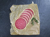 Salami im Käsemantel geschnitten auf Backpapier mit Thymian auf Schieferhintergrund