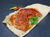 Schweinenackensteak Barbecue mit Basilikum und Peperoni auf Schieferhintergrund