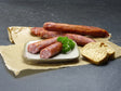 Grobe Mettwurst vom EIFEL Schwein mit Baguettebrot und Petersilie auf Schieferhintergrund