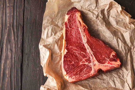 T Bone Steak von der Färse auf Backpapier angerichtet auf Holzhintergrund